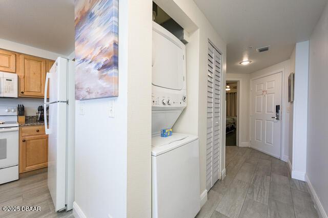 interior space featuring laundry area, stacked washing maching and dryer, visible vents, and baseboards