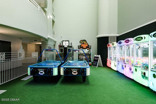 game room with visible vents, carpet flooring, and a towering ceiling