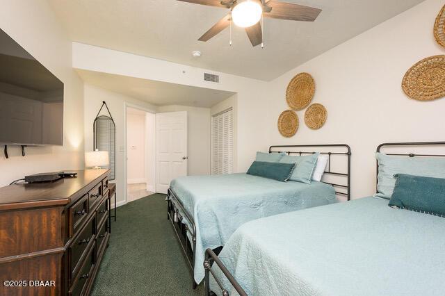 bedroom with dark colored carpet, a closet, visible vents, and a ceiling fan