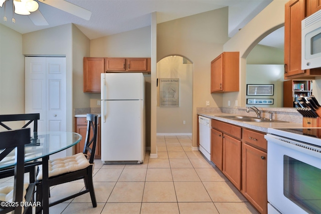 kitchen featuring sink, white appliances, light tile patterned floors, ceiling fan, and vaulted ceiling