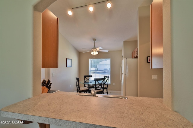 kitchen featuring white refrigerator, lofted ceiling, track lighting, and ceiling fan