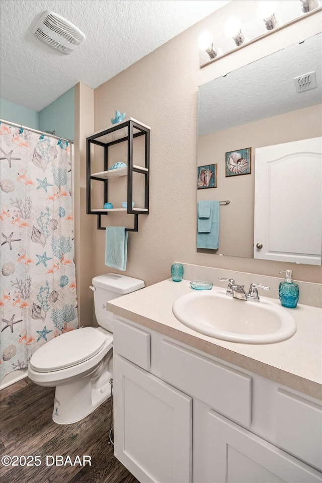 bathroom featuring hardwood / wood-style flooring, vanity, walk in shower, toilet, and a textured ceiling