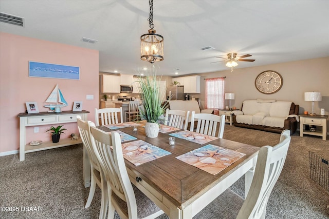 carpeted dining room with ceiling fan with notable chandelier