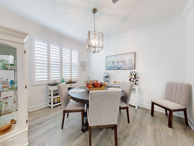 dining space with an inviting chandelier, ornamental molding, and light wood-style flooring