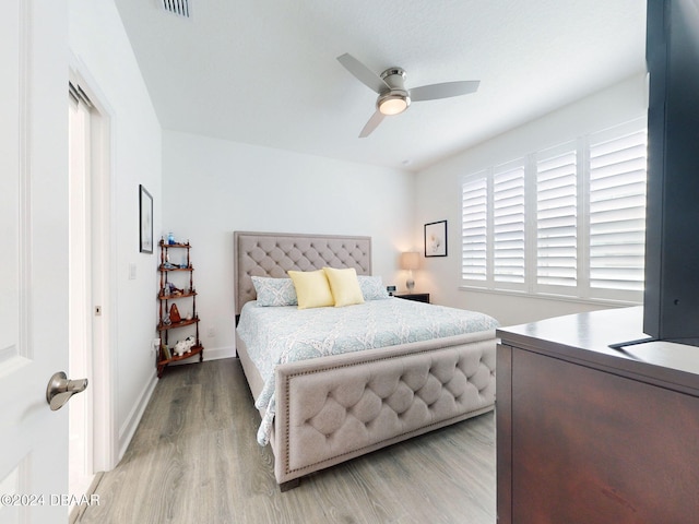 bedroom with baseboards, a ceiling fan, light wood-type flooring, and visible vents