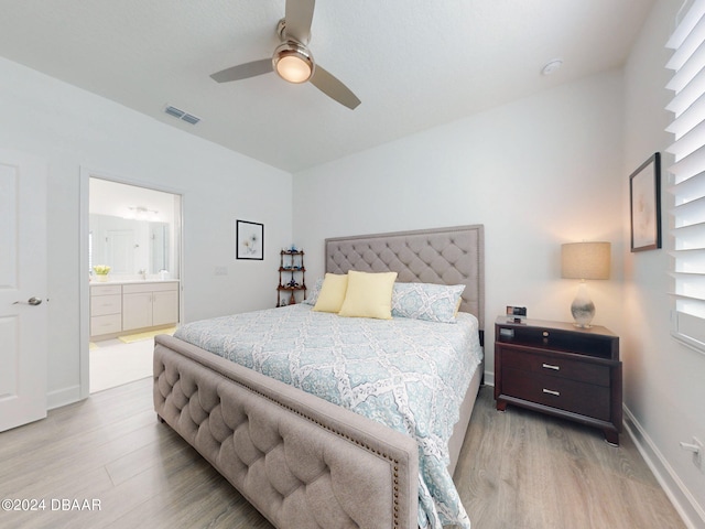 bedroom featuring visible vents, baseboards, a ceiling fan, light wood-style flooring, and ensuite bath
