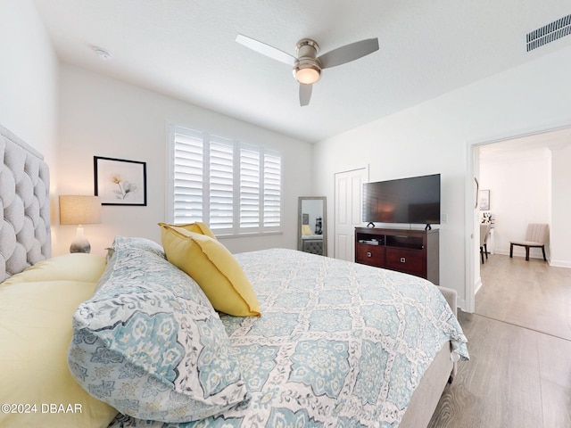 bedroom featuring a ceiling fan, baseboards, visible vents, and wood finished floors