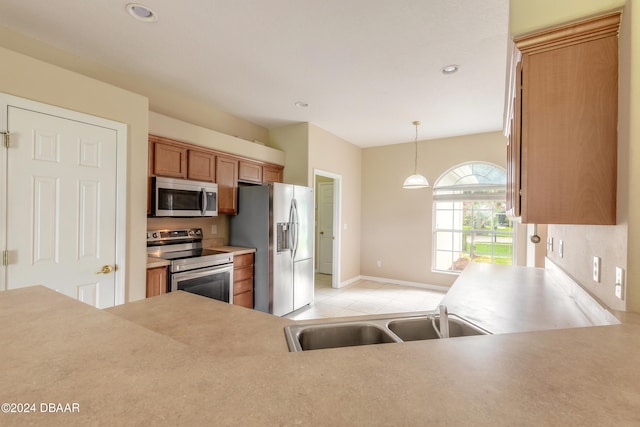 kitchen featuring appliances with stainless steel finishes, hanging light fixtures, sink, and light tile patterned flooring