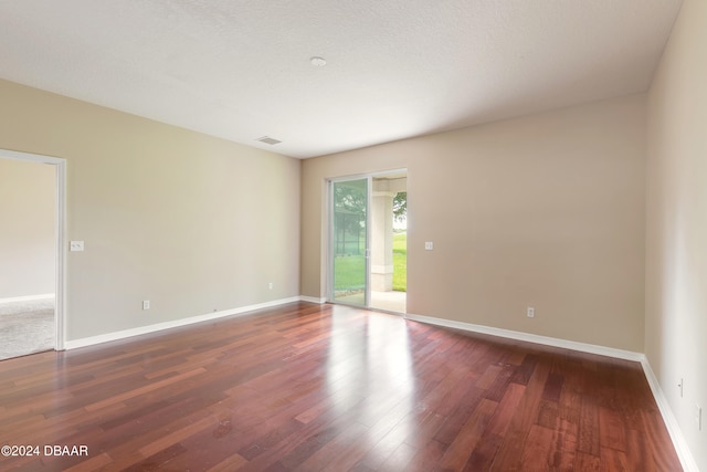 spare room with dark wood-type flooring and a textured ceiling