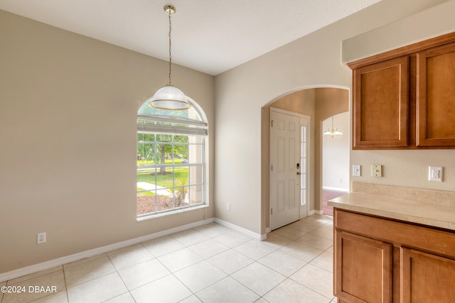 unfurnished dining area featuring light tile patterned flooring and a chandelier