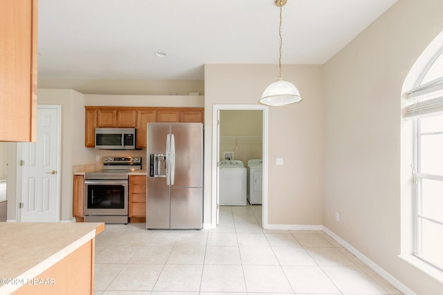 kitchen featuring stainless steel appliances, hanging light fixtures, light tile patterned floors, and washing machine and clothes dryer