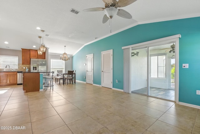 3328 Marsili Ave, New Smyrna Beach, FL 32168 - kitchen featuring vaulted ceiling, crown molding, a sink, ceiling fan with notable chandelier, and appliances with stainless steel finishes