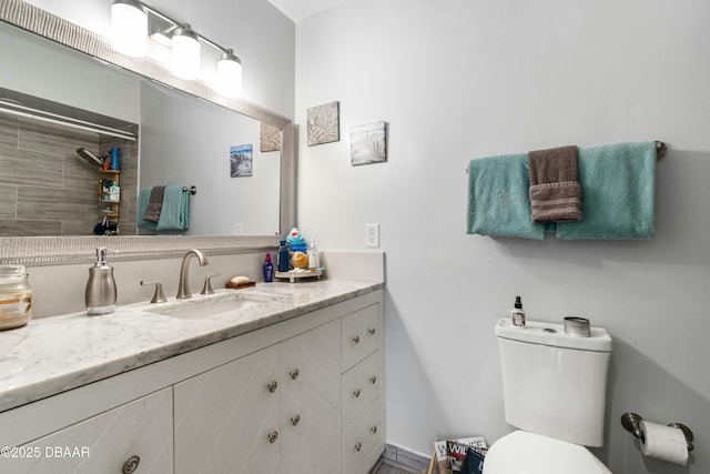 bathroom with vanity, toilet, and a tile shower