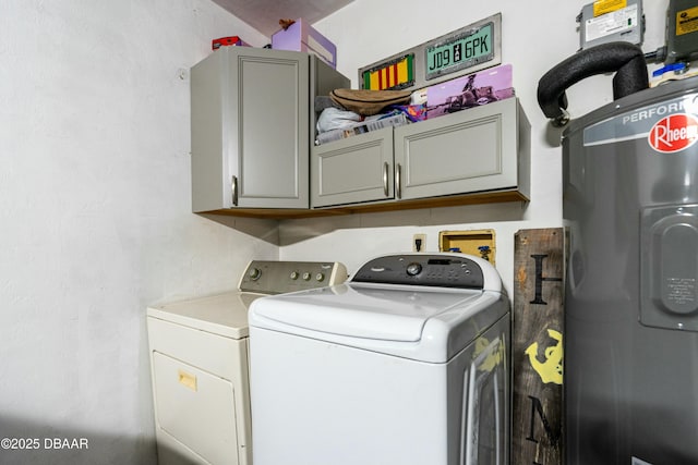 clothes washing area with water heater, cabinets, and washing machine and clothes dryer