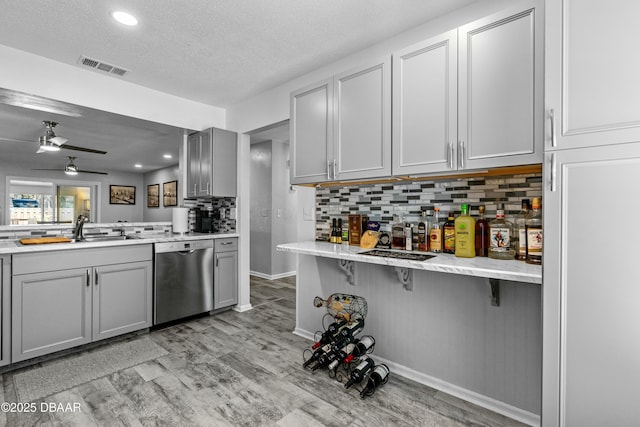 kitchen featuring sink, gray cabinets, light hardwood / wood-style floors, stainless steel dishwasher, and kitchen peninsula