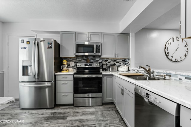 kitchen featuring tasteful backsplash, stainless steel appliances, sink, and gray cabinetry