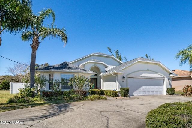 ranch-style house with fence, a garage, driveway, and stucco siding