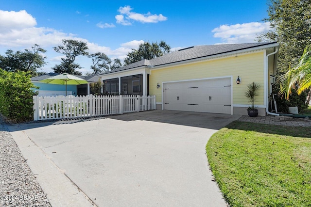 ranch-style home featuring a garage, a front lawn, and a sunroom