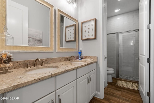 bathroom with wood-type flooring, toilet, vanity, and a shower with shower door