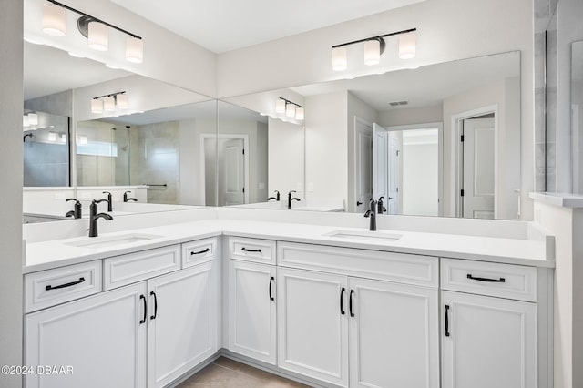 bathroom with tile patterned flooring, vanity, and a tile shower