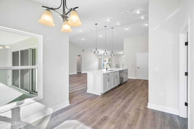 kitchen featuring hanging light fixtures, light hardwood / wood-style floors, a center island with sink, and sink