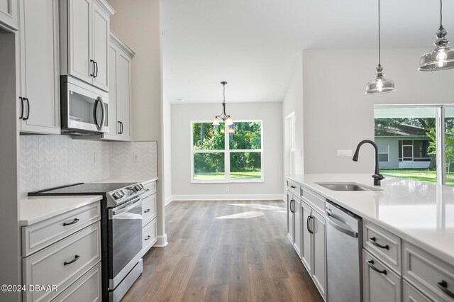 kitchen with stainless steel appliances, plenty of natural light, sink, and pendant lighting