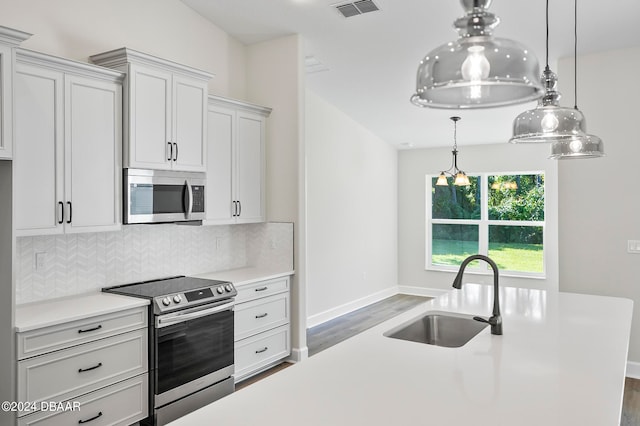 kitchen featuring stainless steel appliances, dark hardwood / wood-style flooring, sink, backsplash, and pendant lighting