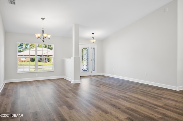 unfurnished living room featuring a notable chandelier and dark hardwood / wood-style floors