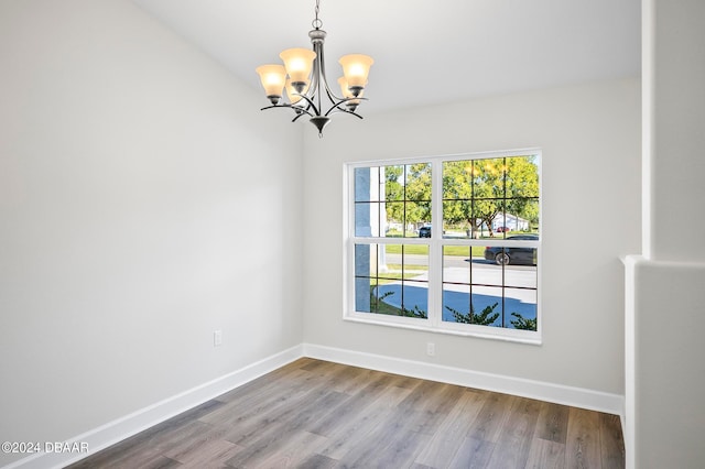 spare room with hardwood / wood-style floors and a notable chandelier