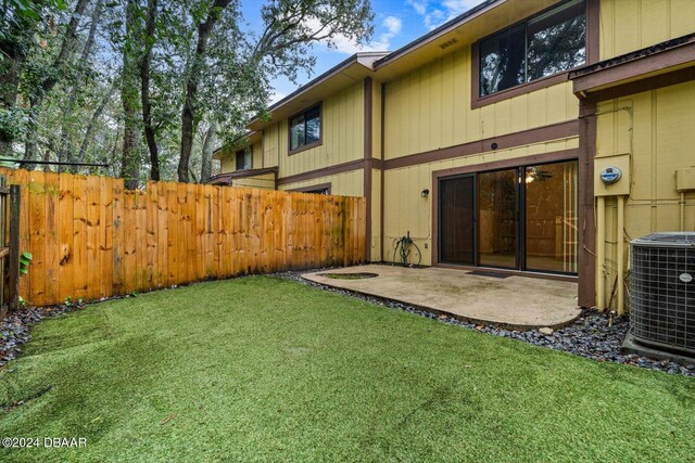 rear view of house with central air condition unit, a patio area, and a lawn