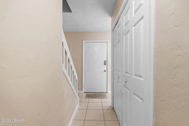 corridor with light tile patterned floors and a textured ceiling