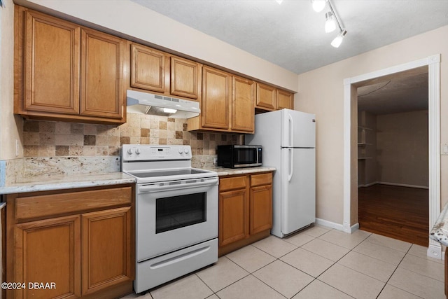 kitchen with backsplash, light tile patterned floors, and white appliances