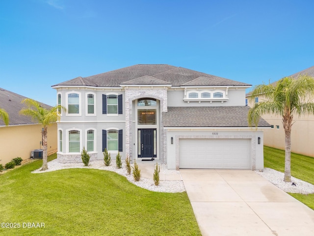 view of front of home with a garage, cooling unit, and a front yard