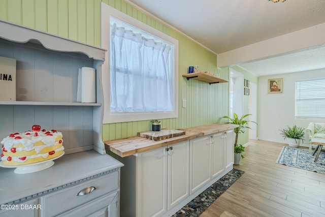 kitchen with white cabinetry, a textured ceiling, wooden counters, and light wood-type flooring