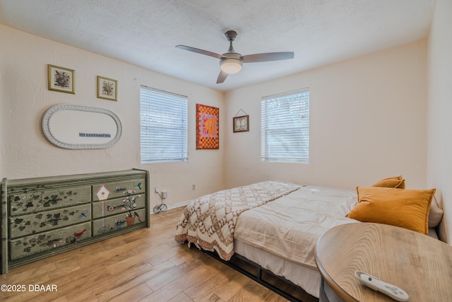 bedroom with ceiling fan, a textured ceiling, and light wood-type flooring