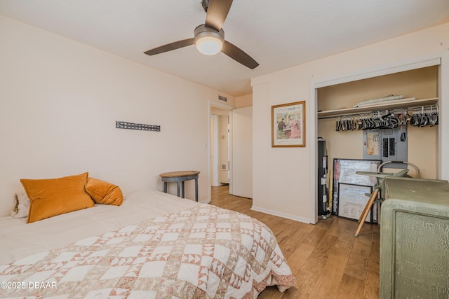 bedroom featuring water heater, ceiling fan, light hardwood / wood-style floors, and a closet