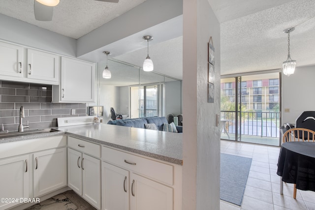 kitchen featuring white cabinets, sink, pendant lighting, and decorative backsplash