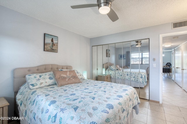 bedroom with light tile patterned floors, ceiling fan, a textured ceiling, and a closet