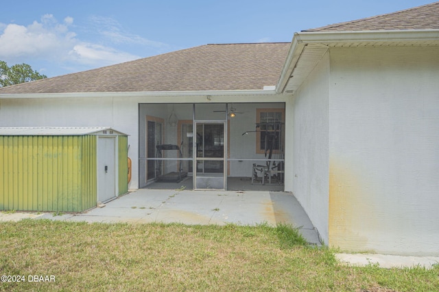 back of property with a patio area, a sunroom, a yard, and a storage unit