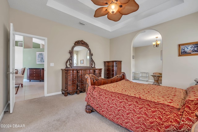 carpeted bedroom with a raised ceiling and ceiling fan