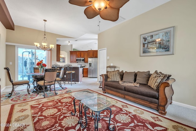 carpeted living room with ceiling fan with notable chandelier and vaulted ceiling