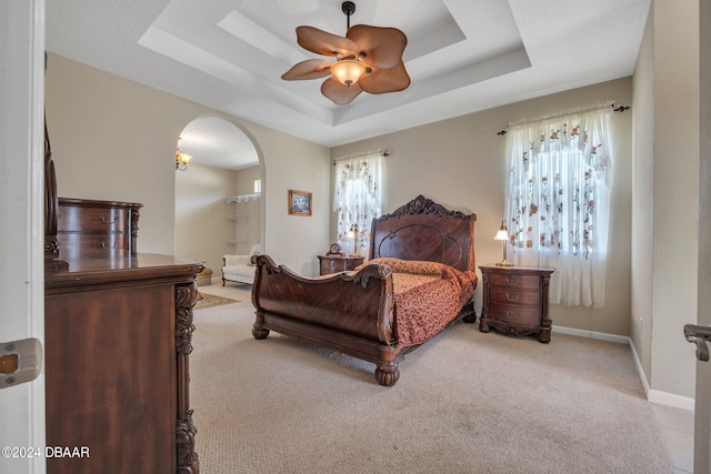 carpeted bedroom with a tray ceiling and ceiling fan