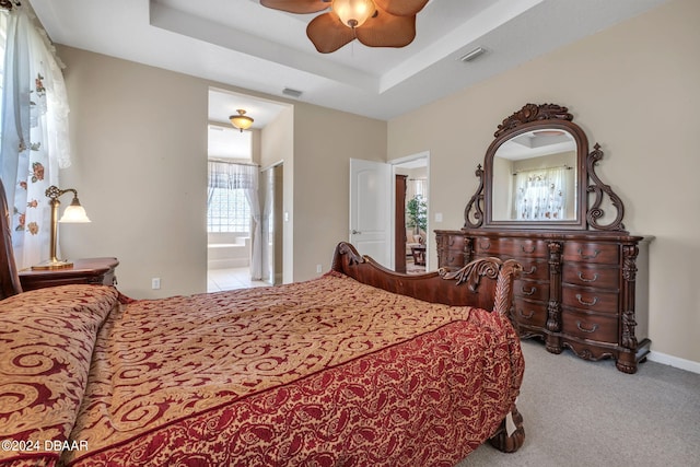 carpeted bedroom featuring a raised ceiling, ceiling fan, and ensuite bathroom