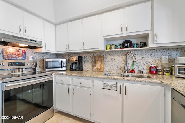 kitchen with light stone counters, stainless steel appliances, light tile patterned floors, sink, and white cabinets