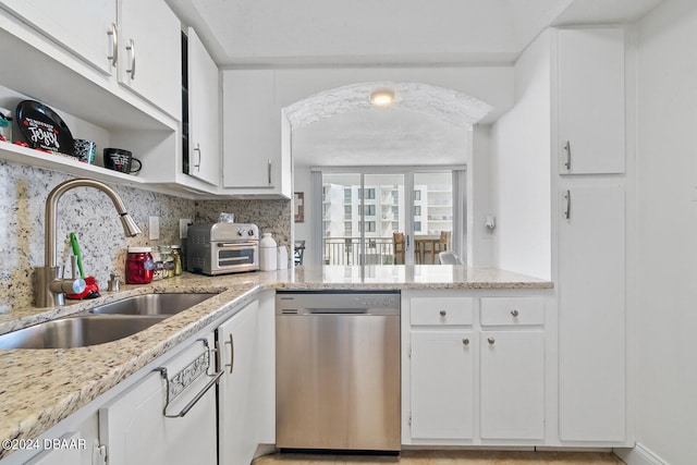 kitchen featuring light stone counters, dishwasher, white cabinets, sink, and backsplash