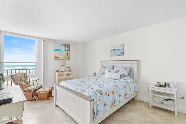 tiled bedroom featuring a water view and a textured ceiling