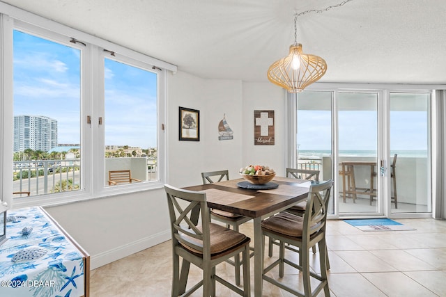 tiled dining room featuring a water view and a textured ceiling