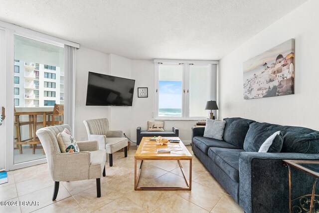 living room with a wealth of natural light, a textured ceiling, and tile patterned floors