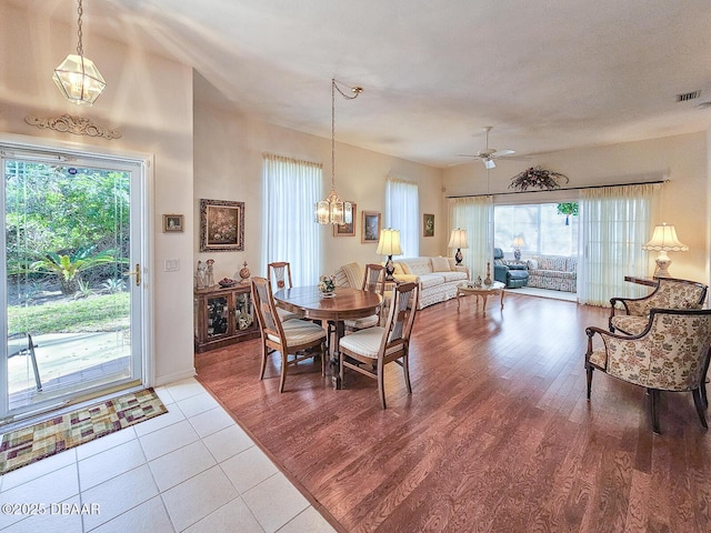 dining area with ceiling fan with notable chandelier, hardwood / wood-style floors, and a wealth of natural light