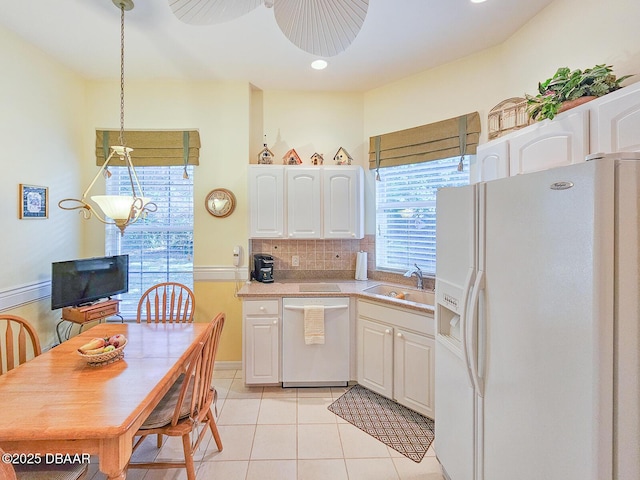 kitchen featuring sink, white refrigerator with ice dispenser, stainless steel dishwasher, and white cabinets